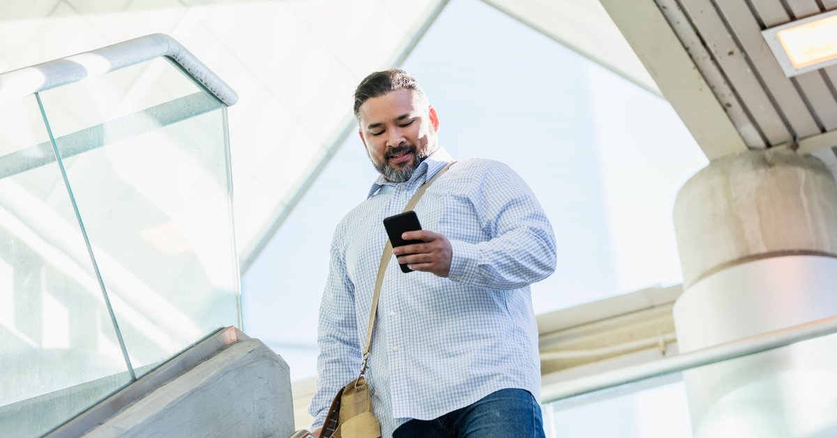 A person walking down stairs while smiling and looking at their phone.
