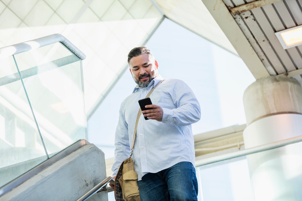 A person walking down stairs while smiling and looking at their phone.