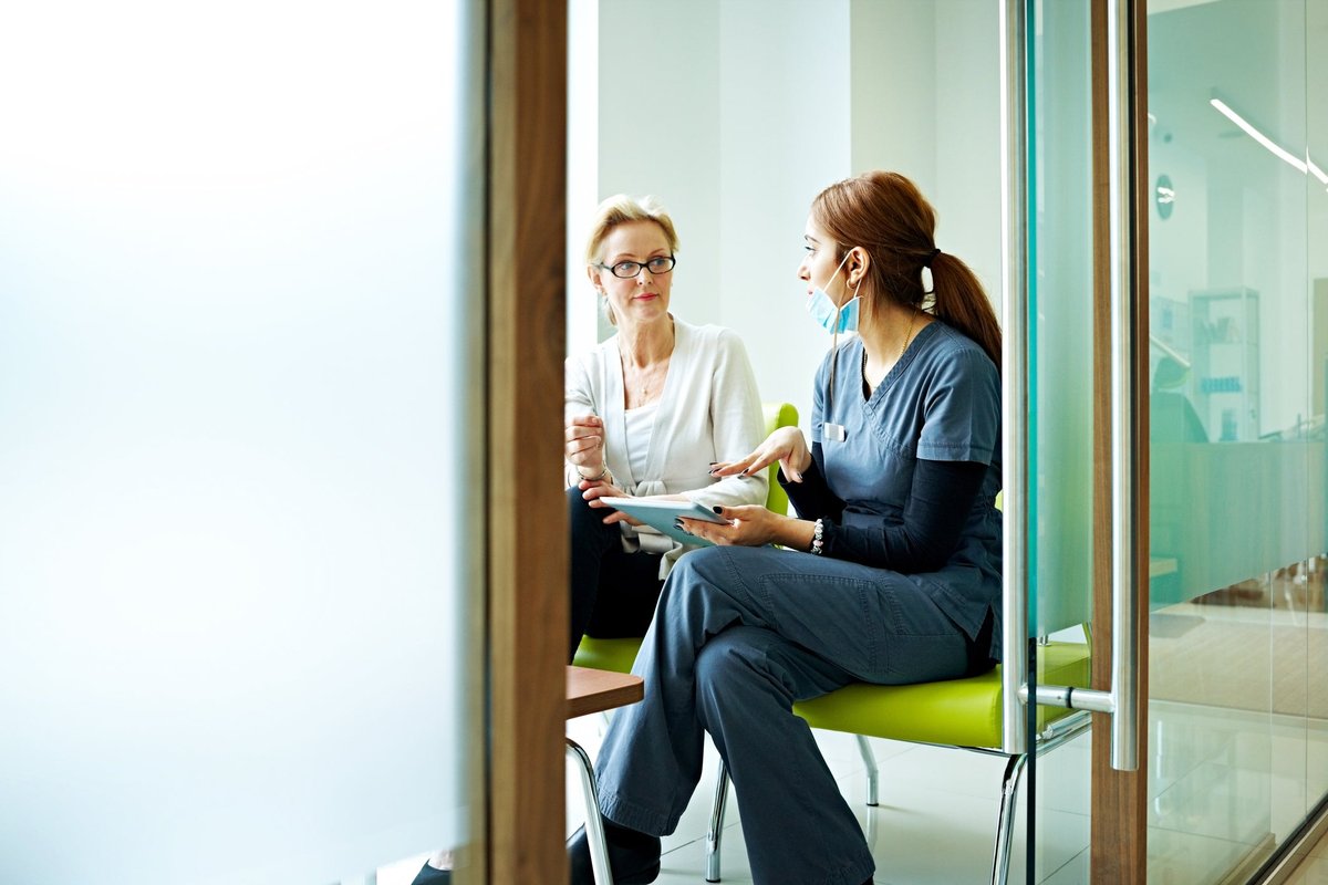 A patient speaking with a medical professional in an exam room.