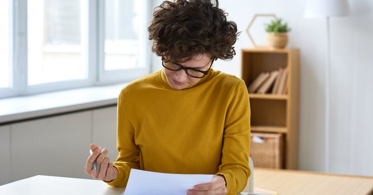 A person sitting at a desk and filling out paperwork.
