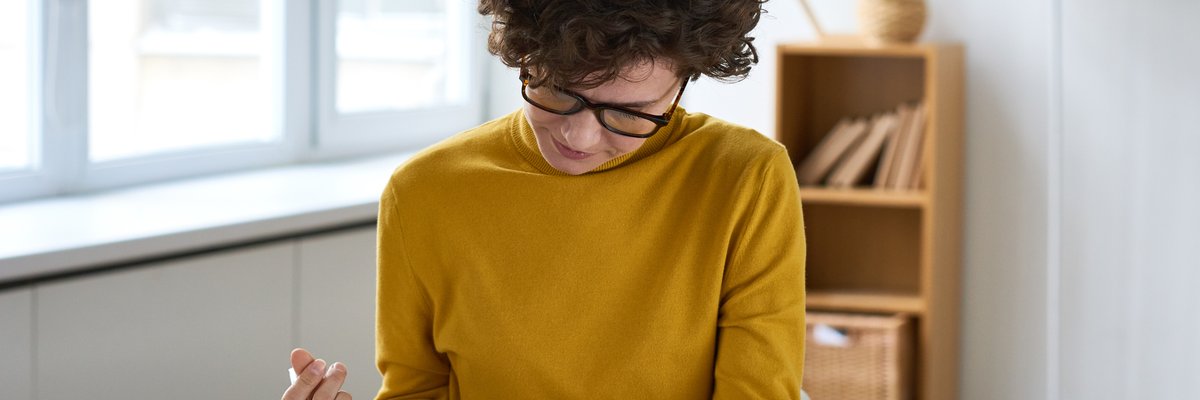 A person sitting at a desk and filling out paperwork.