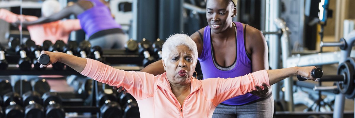 Senior citizen works out in a gym with a personal trainer.