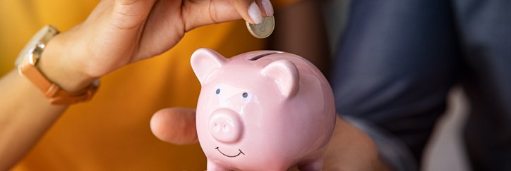 woman putting change into piggy bank.