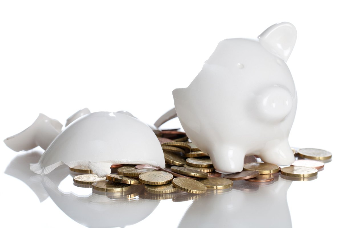 Broken piggy bank with coins spilled out of it.