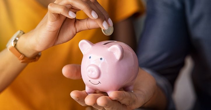 woman putting change into piggy bank.