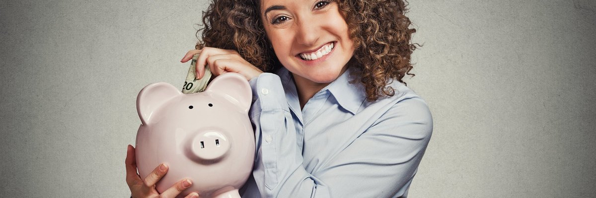 Smiling woman putting money into piggy bank. 