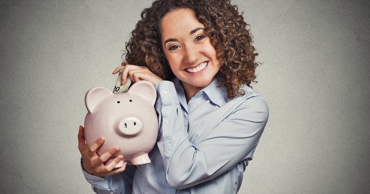 Smiling woman putting money into piggy bank. 