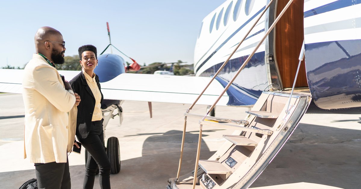 Two well-dressed people boarding a private plane on the tarmac.