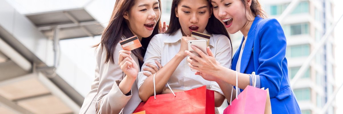 three girls holding shopping bags and credit cards taking a selfie