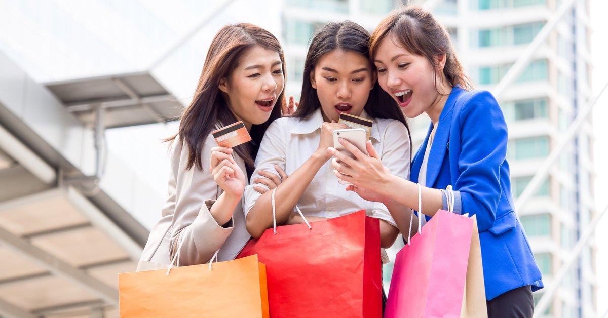 three girls holding shopping bags and credit cards taking a selfie