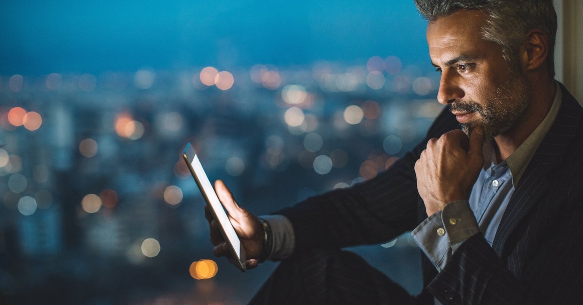 Professionally dressed man smiles as he looks at his cell phone.