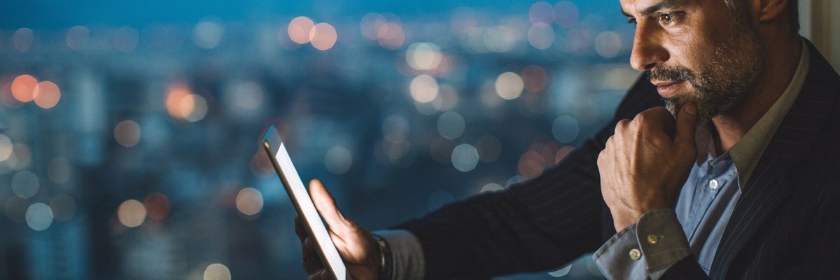 Professionally dressed man smiles as he looks at his cell phone.
