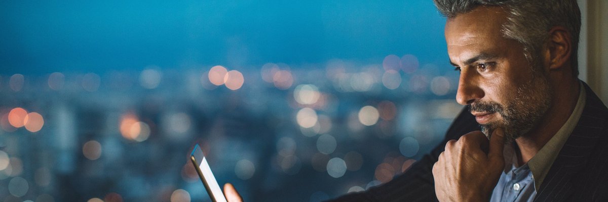 Professionally dressed man smiles as he looks at his cell phone.