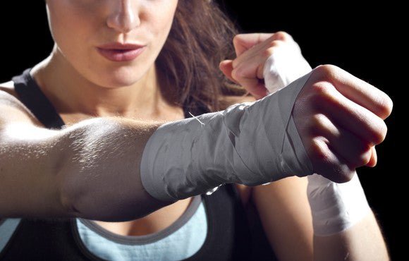 close up of woman with taped wrists defending herself and throwing a punch