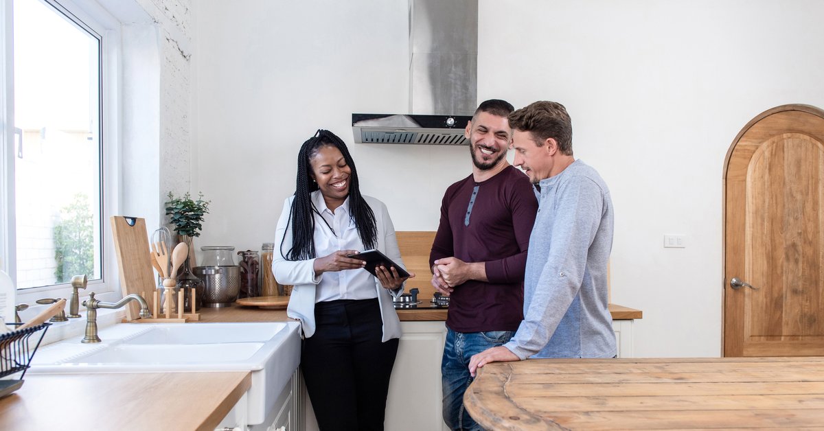 A realtor showing a smiling couple a new home.
