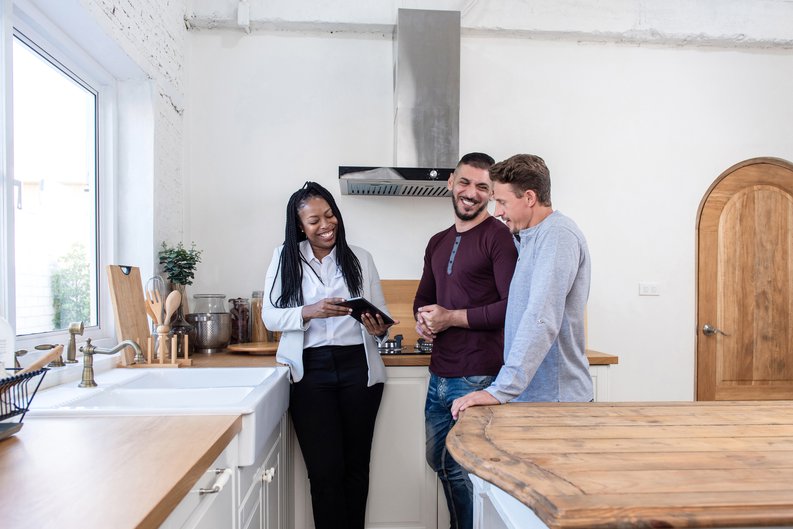A realtor showing a smiling couple a new home.