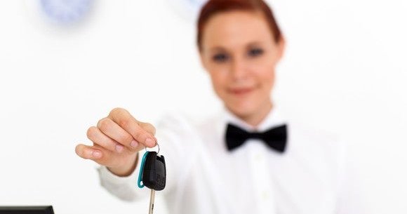 car rental company employee handing over car key to client