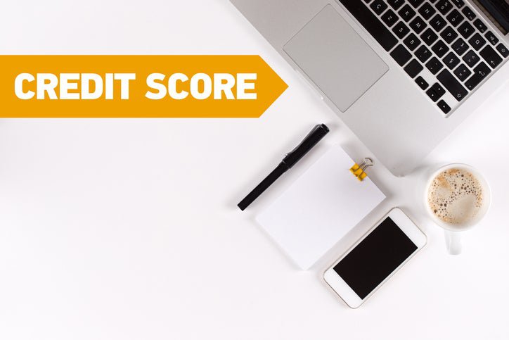 A laptop, coffee, pen, pad, and phone next to the words "credit score."