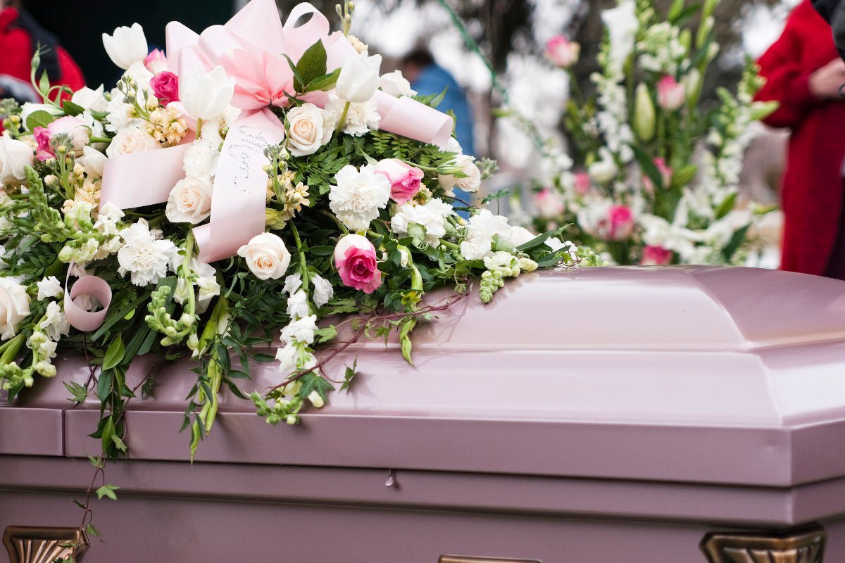 A bouquet of roses on top of a silver coffin.