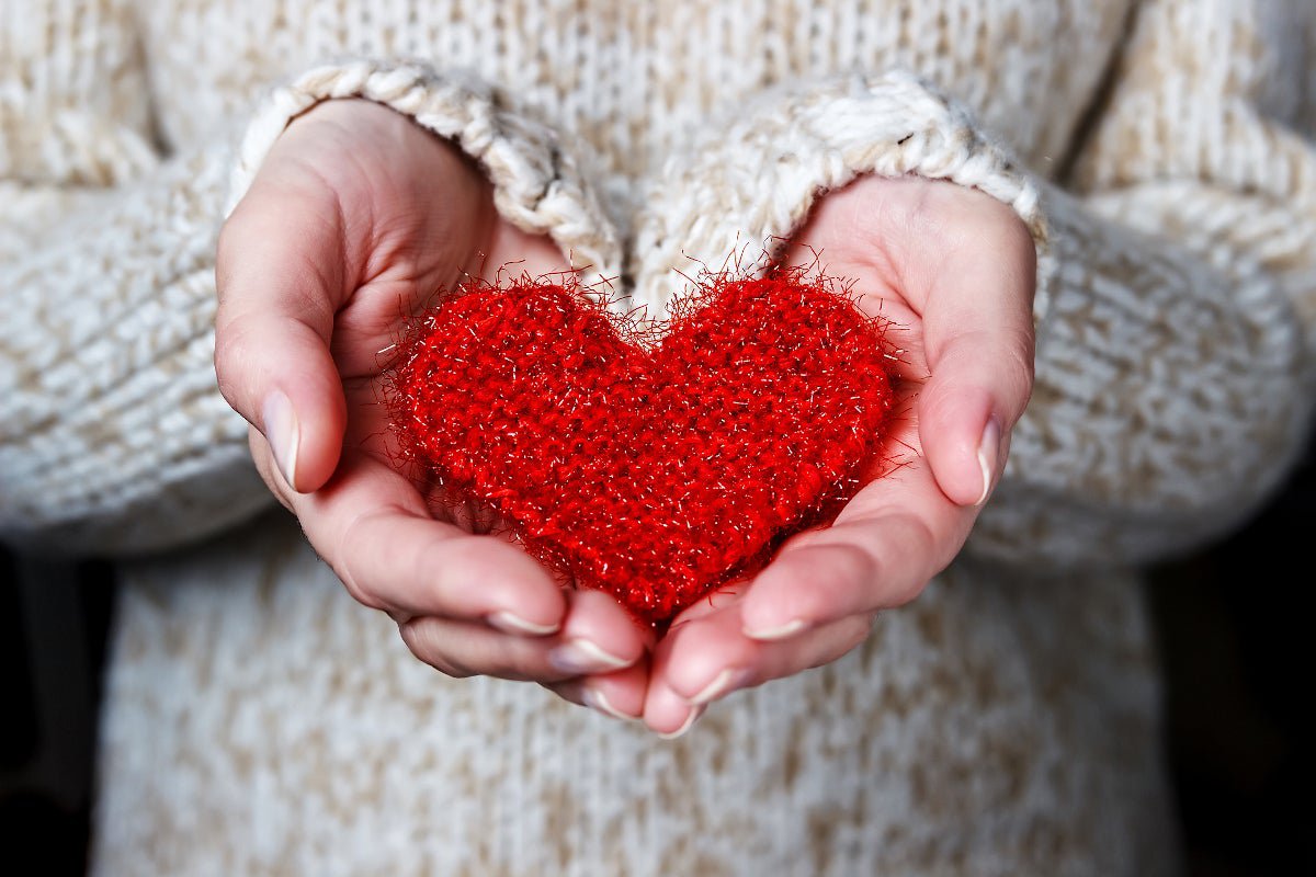 A women holding a knit heart in the palms of her hands.