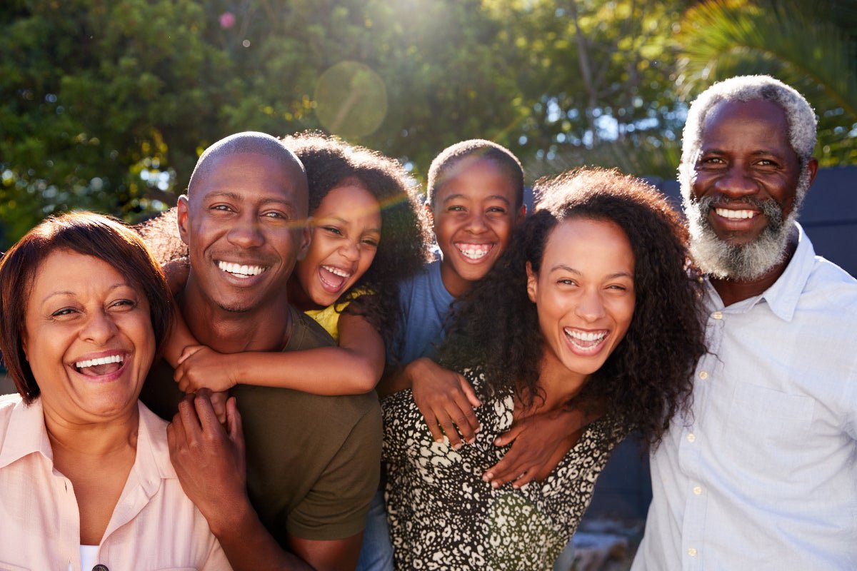 A family of six smiling outdoors on a sunny day.