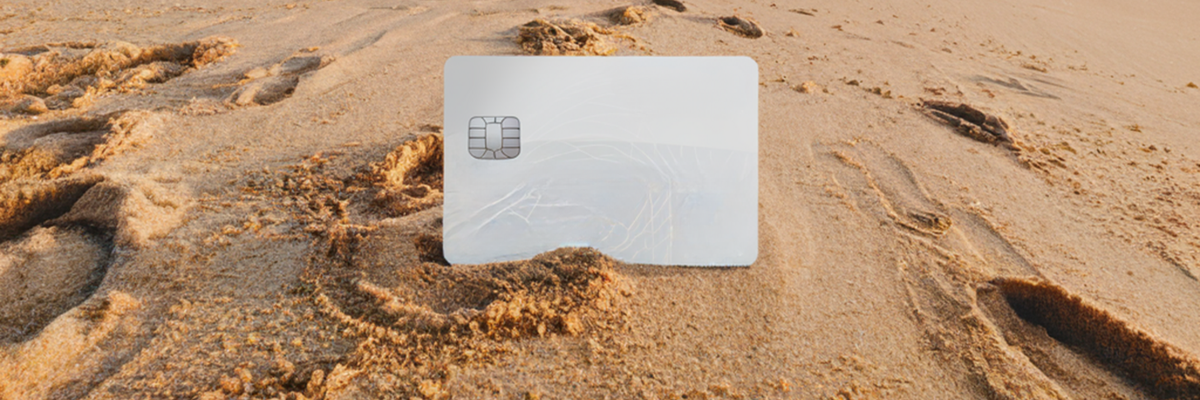 A generic silver credit card in the sand on the beach.