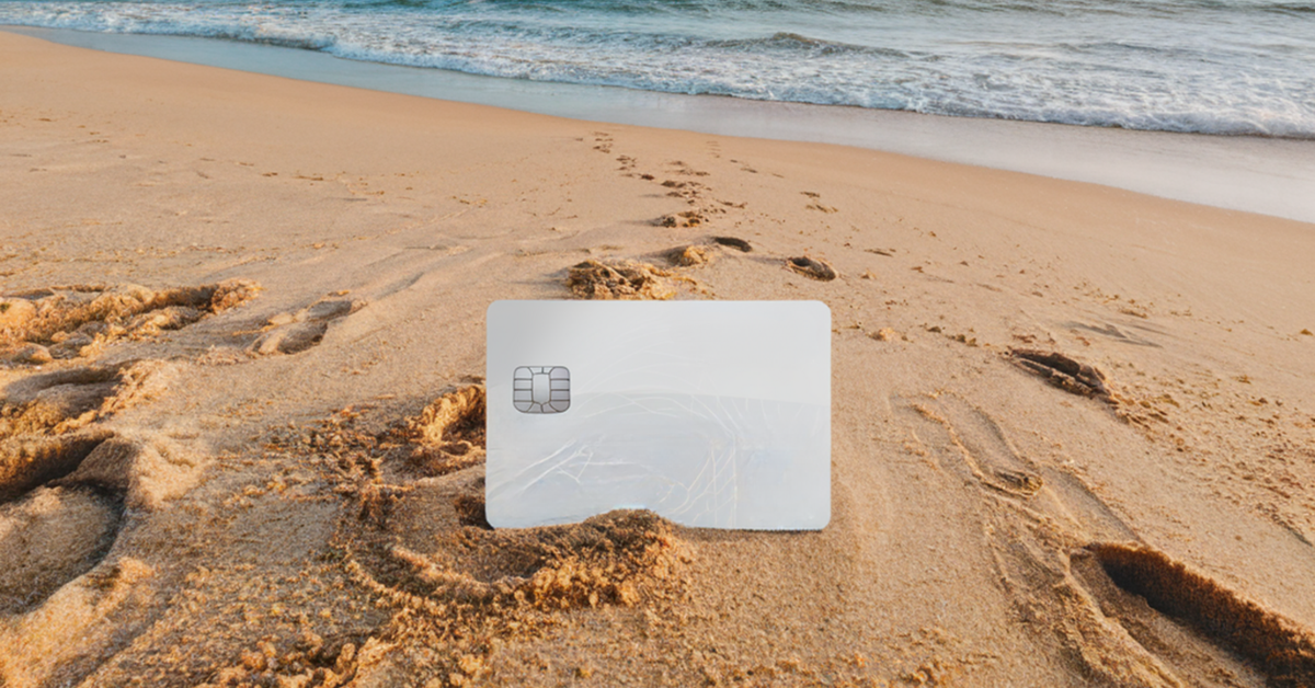 A generic silver credit card in the sand on the beach.