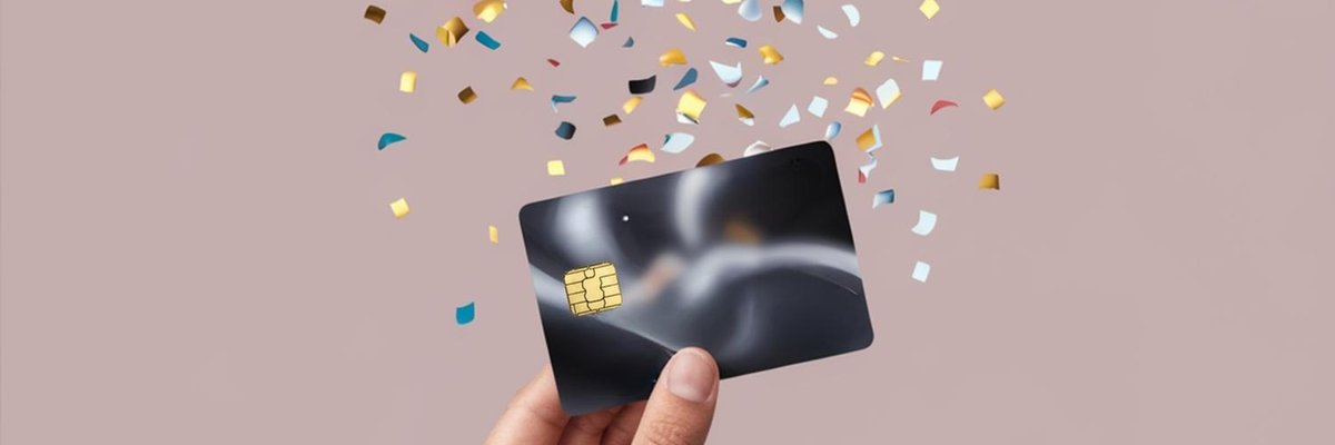 A hand holds up a generic credit card that's surrounded by confetti.