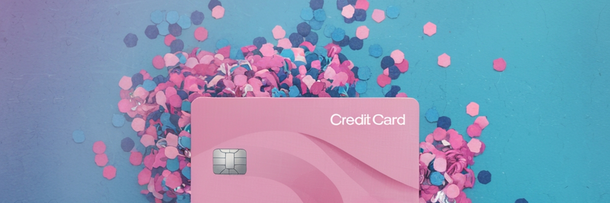 A generic pink credit card laying on a pile of pink and blue confetti.