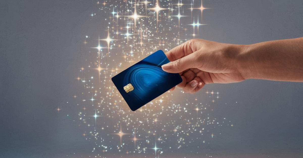 A hand holding a generic blue credit card with sparkles falling all around it.