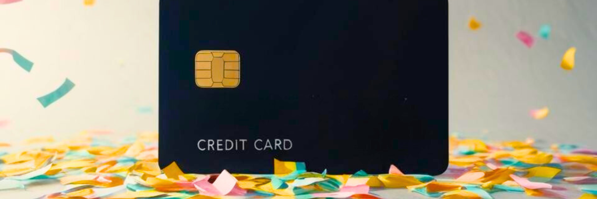 A plain black credit card surrounded by pastel-colored confetti.
