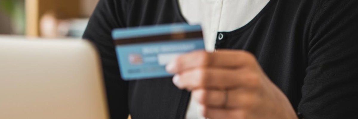 Woman holds credit cards in front of her while she uses laptop.