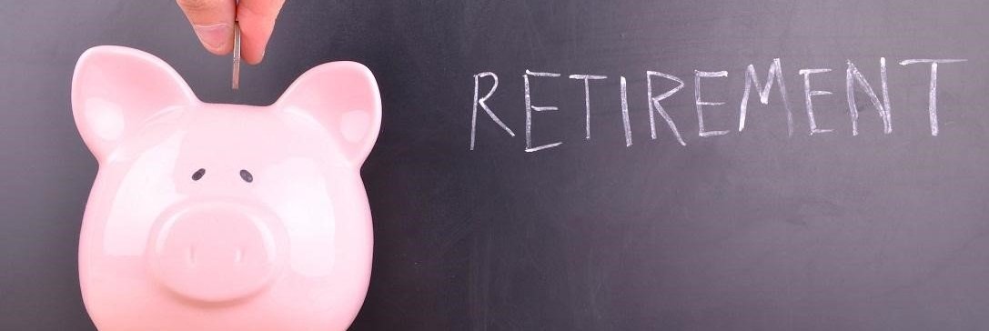 A hand putting coins into a piggy bank with the word Retirement behind it on a chalk board.