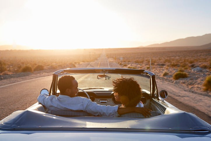 A couple on the road in a convertible.