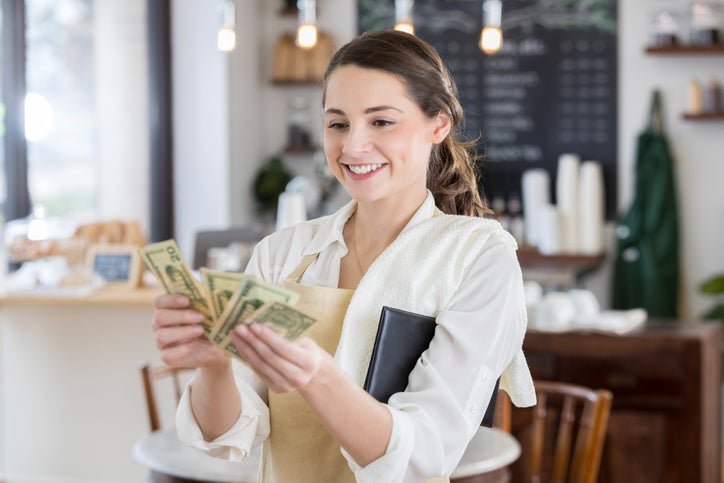 A woman counts dollar bills at her job.