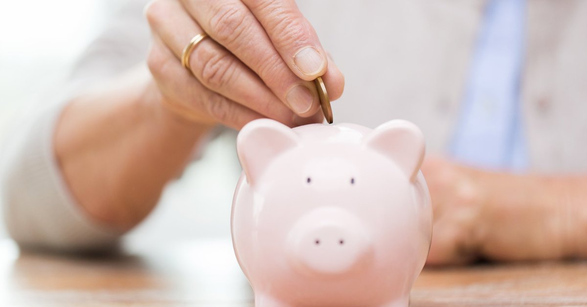 Woman dropping coin into piggy bank