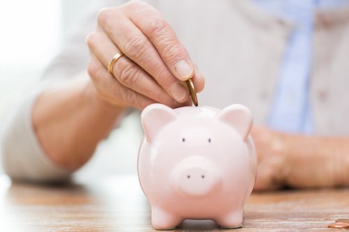 hand inserting quarter into piggy bank