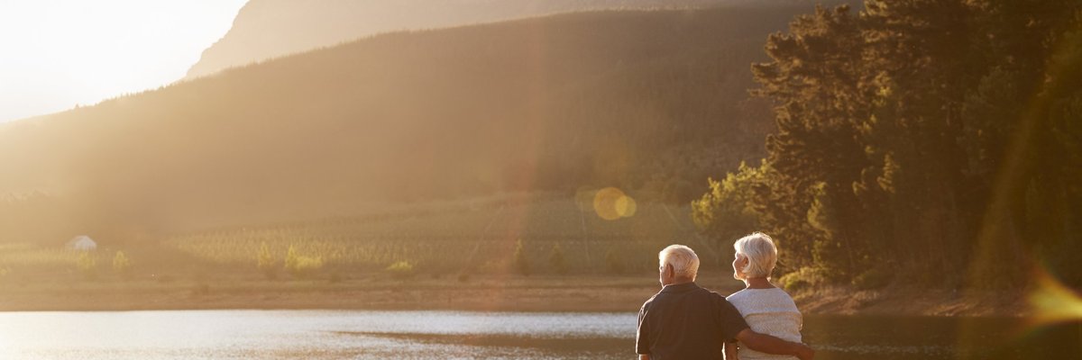 senior man and woman sitting at the end of a dock on a lake_retirement relaxing vacation