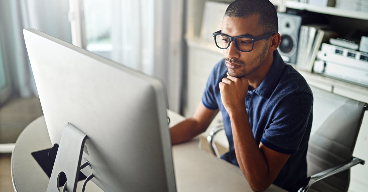 A serious young man working on his computer at home.