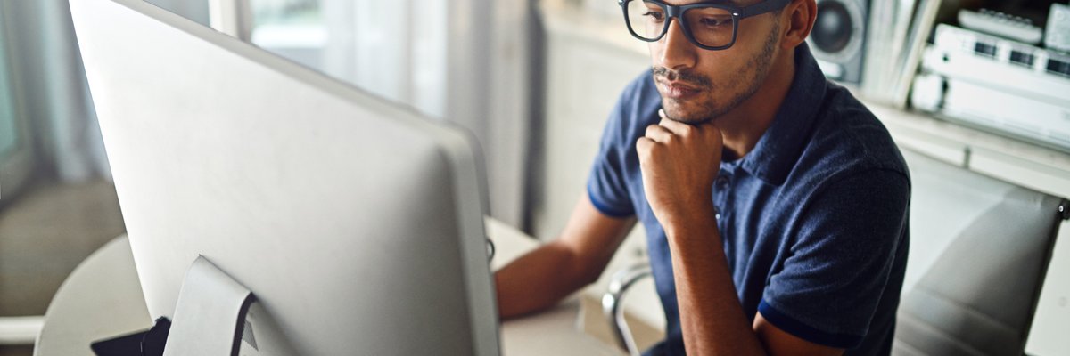 A serious young man working on his computer at home.