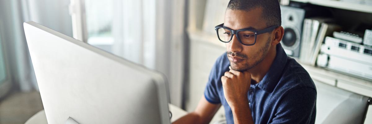 A serious young man working on his computer at home.