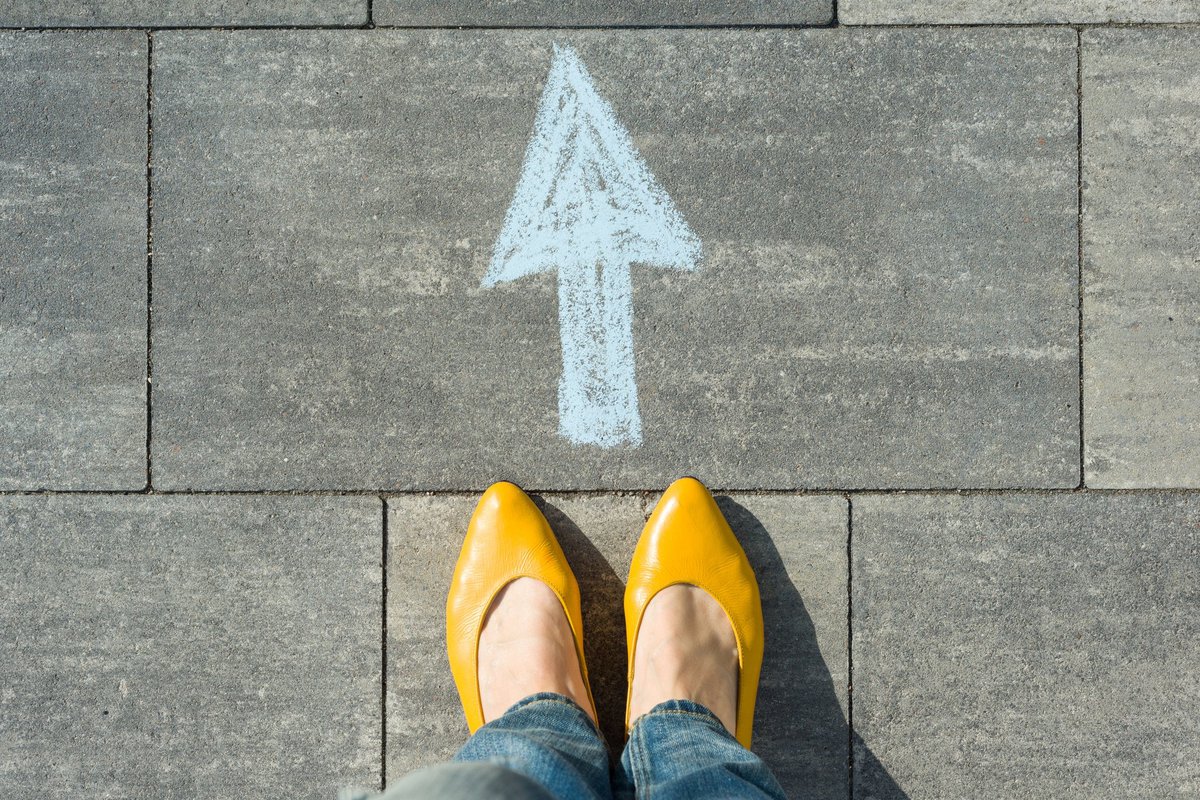 woman's feet standing behind an arrow pointing forward