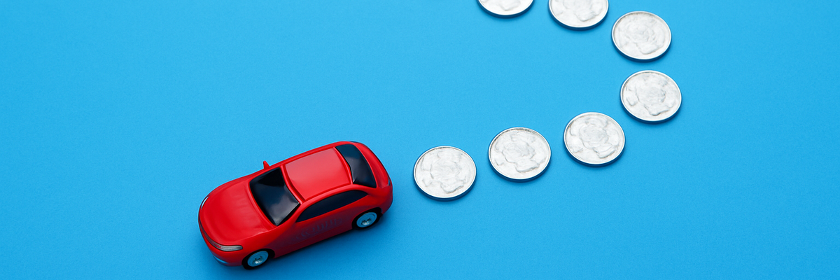 A small red car with a trail of silver coins in a shape of track on blue background.