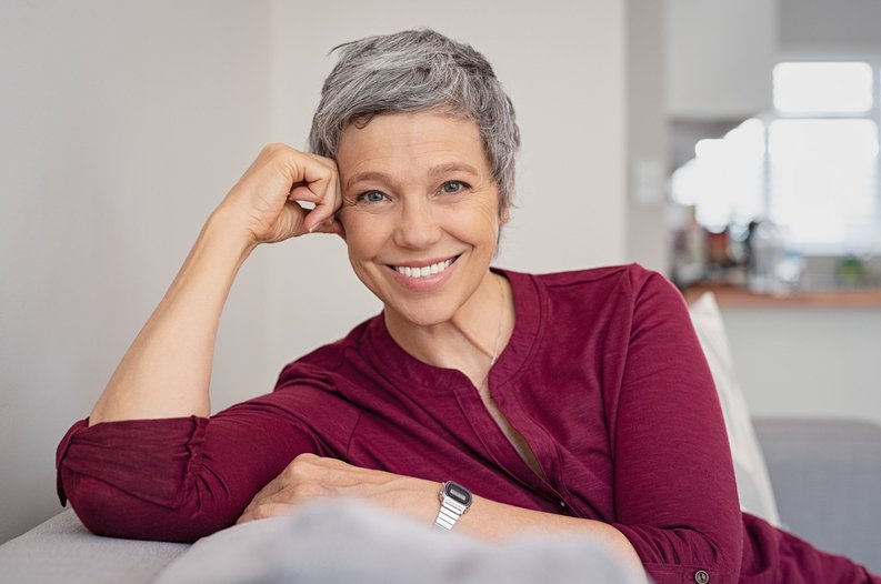 Smiling older woman resting hand against head