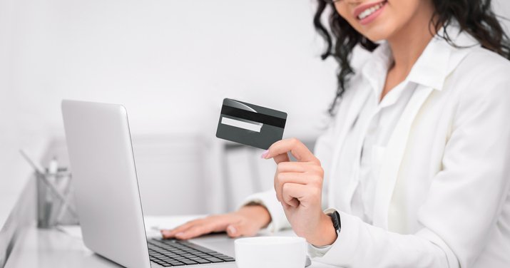 A smiling woman holds a credit card.