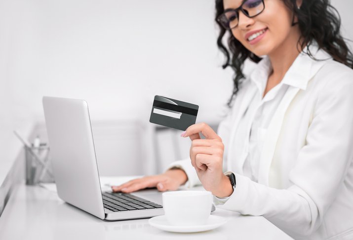 A smiling woman holds a credit card.