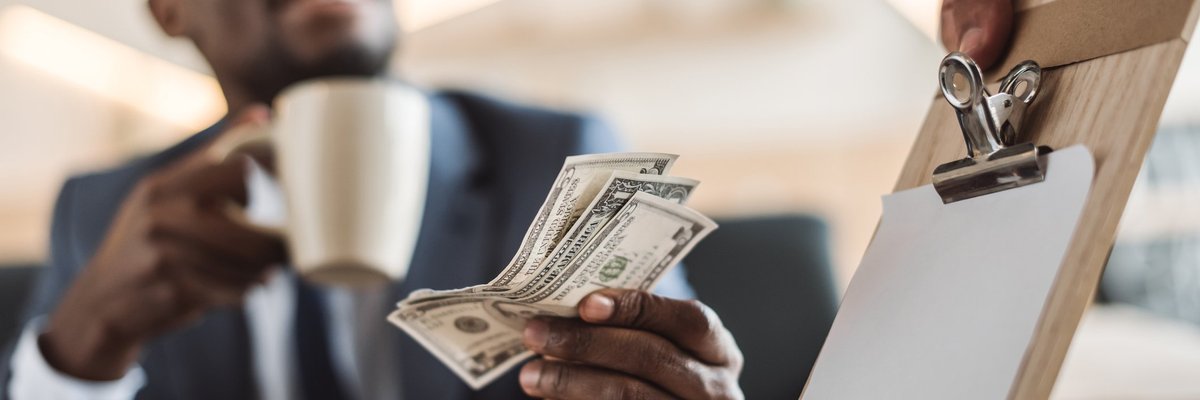 smiling young man holding a coffee mug and handing cash to a waiter