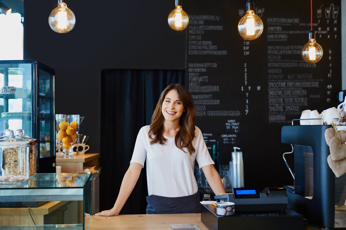 smiling young woman standing behind the counter in a cafe