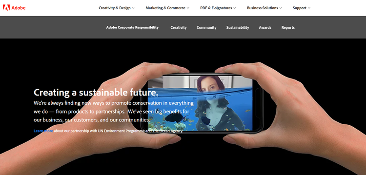A note about sustainability on the Adobe website set over two hands holding a smartphone.
