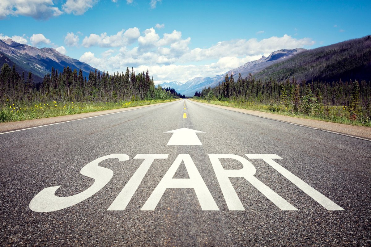 The word START written on a road in a forested area.